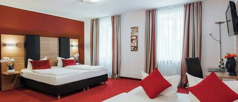 A hotel room with a large bed, a sofa, a desk, and a TV.