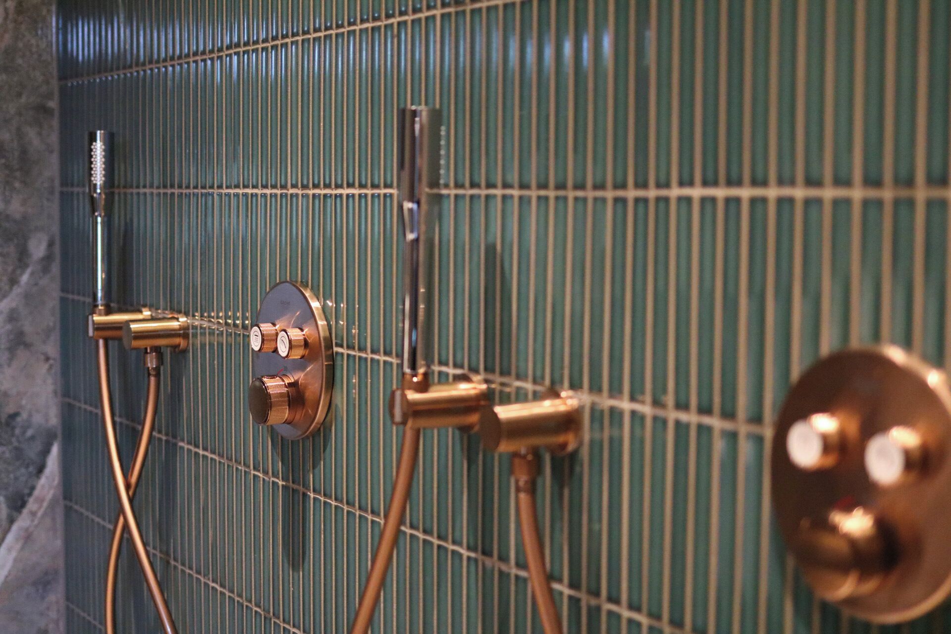 A shower with a control panel and a handheld showerhead.