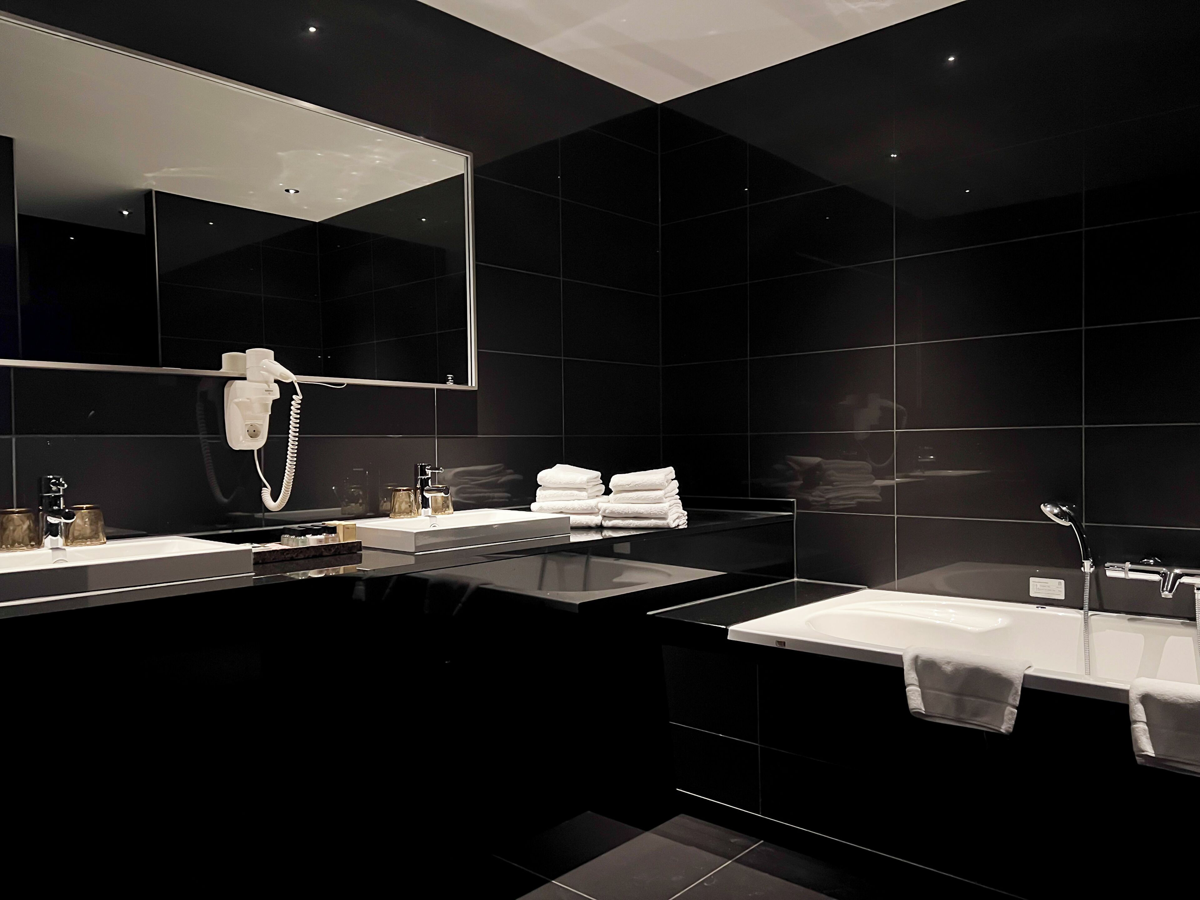 A modern bathroom with two sinks, a large mirror, and a hairdryer.