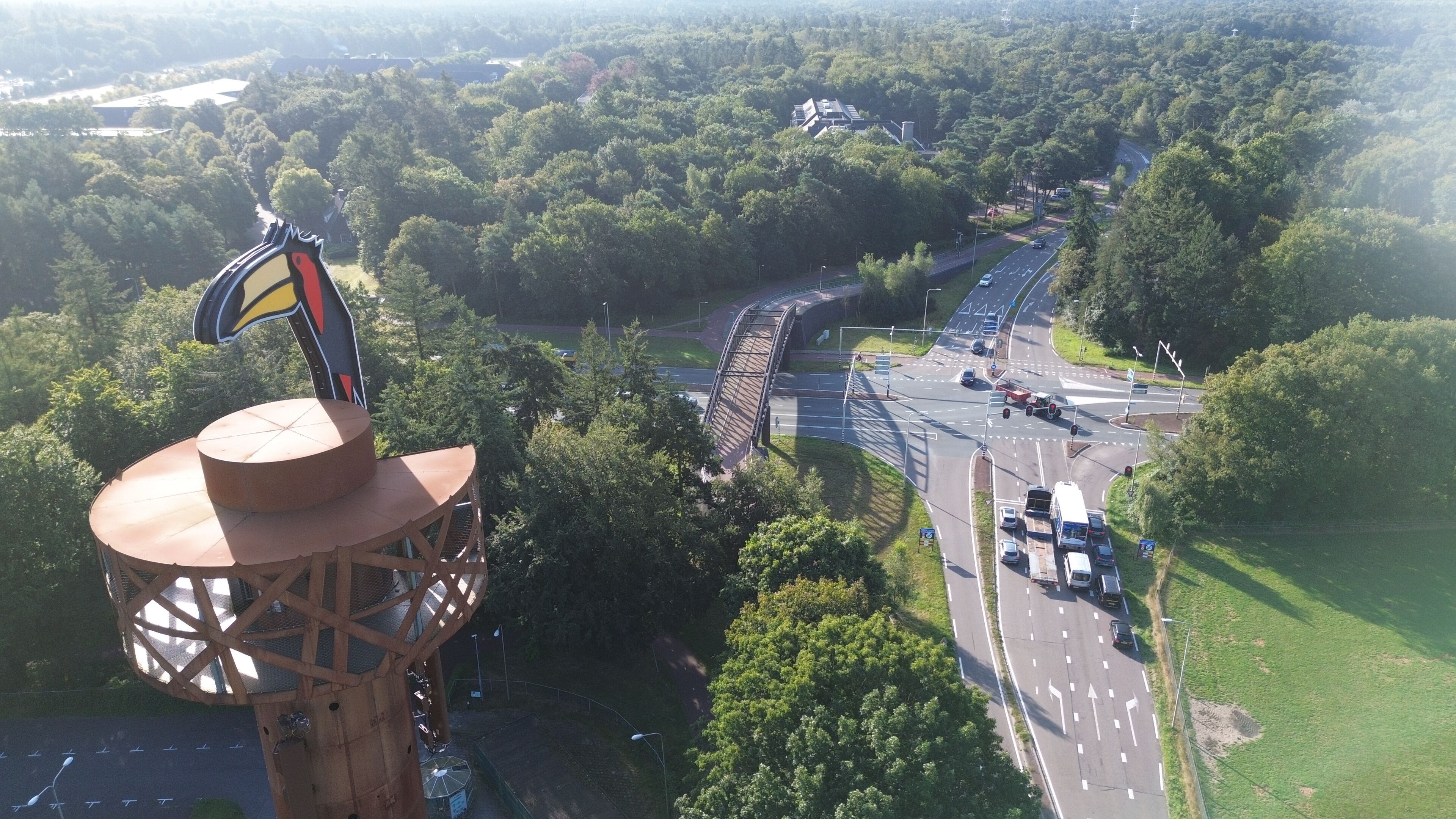 A tower with a flag, a bridge, and a road with vehicles.