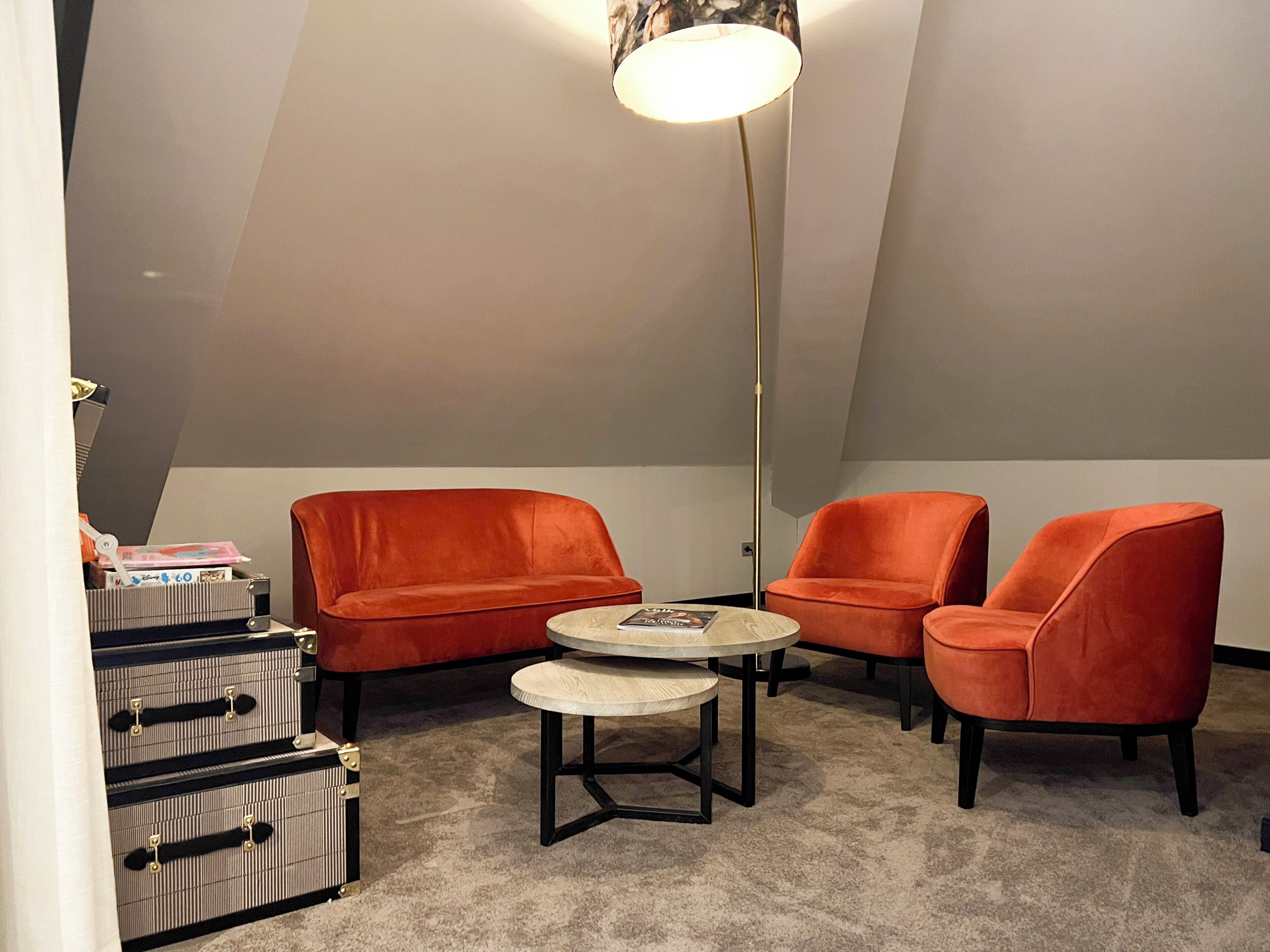 A room with a sloped ceiling, a round table, two chairs, and a lamp.