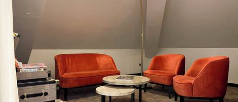 A room with a sloped ceiling, a round table, two chairs, and a lamp.