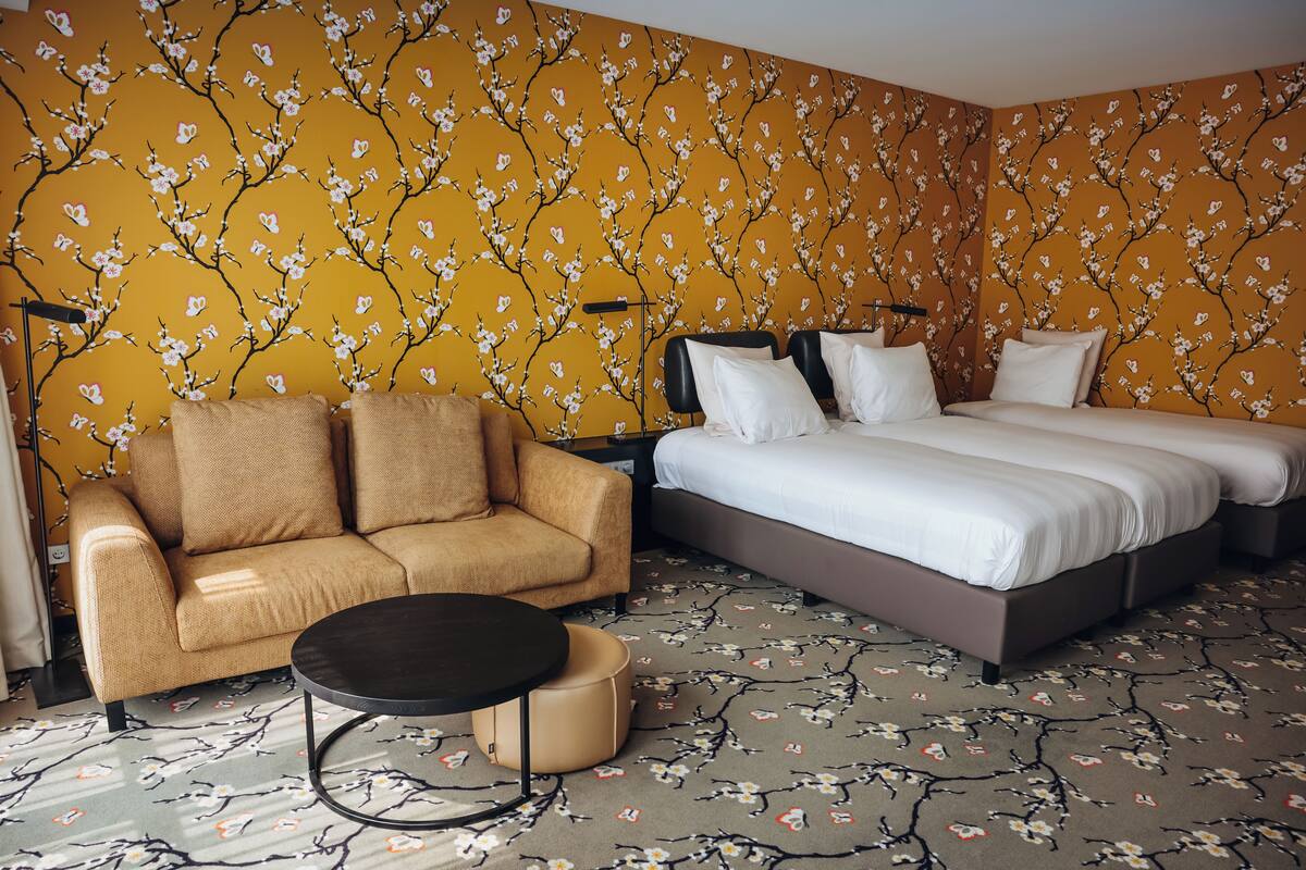Ein Hotelzimmer mit einer Couch, einem runden Tisch und einem Bett mit weißer Bettwäsche.