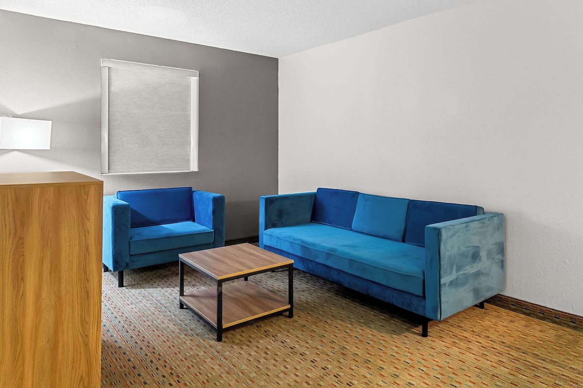 A room with a blue sofa, a matching armchair, and a small wooden table.