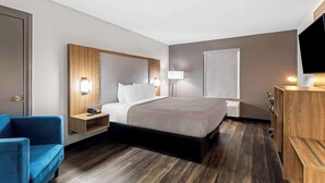 Una camera d'albergo con un letto, comodini, una scrivania, una sedia, una TV e un armadio.