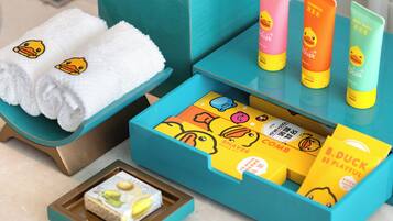 A bathroom with a teal vanity, white towels with duck designs, and various toiletries including a toothbrush and toothpaste.