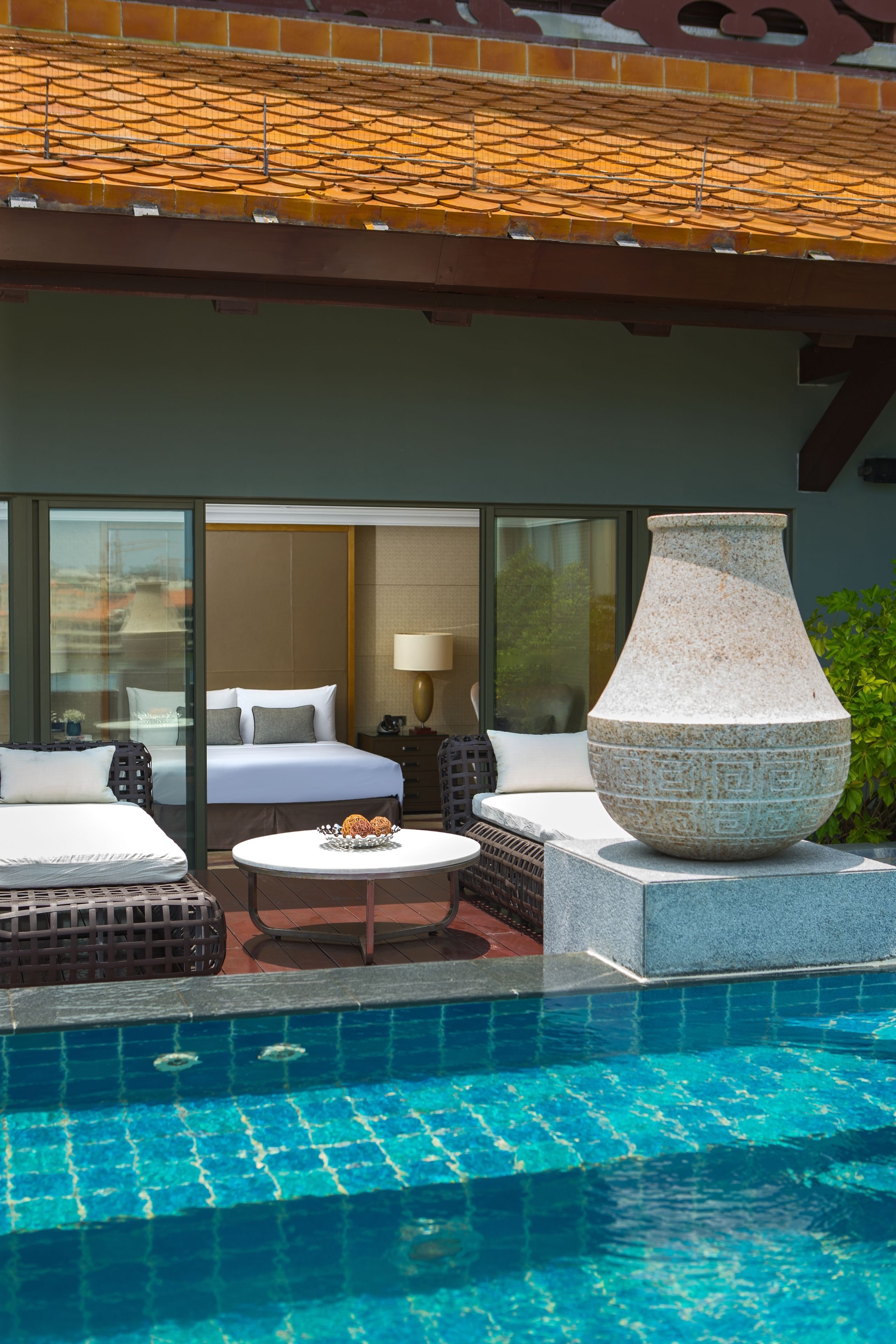 Une chambre d’hôtel avec un grand lit, un coin salon avec une table et une vue sur la piscine.