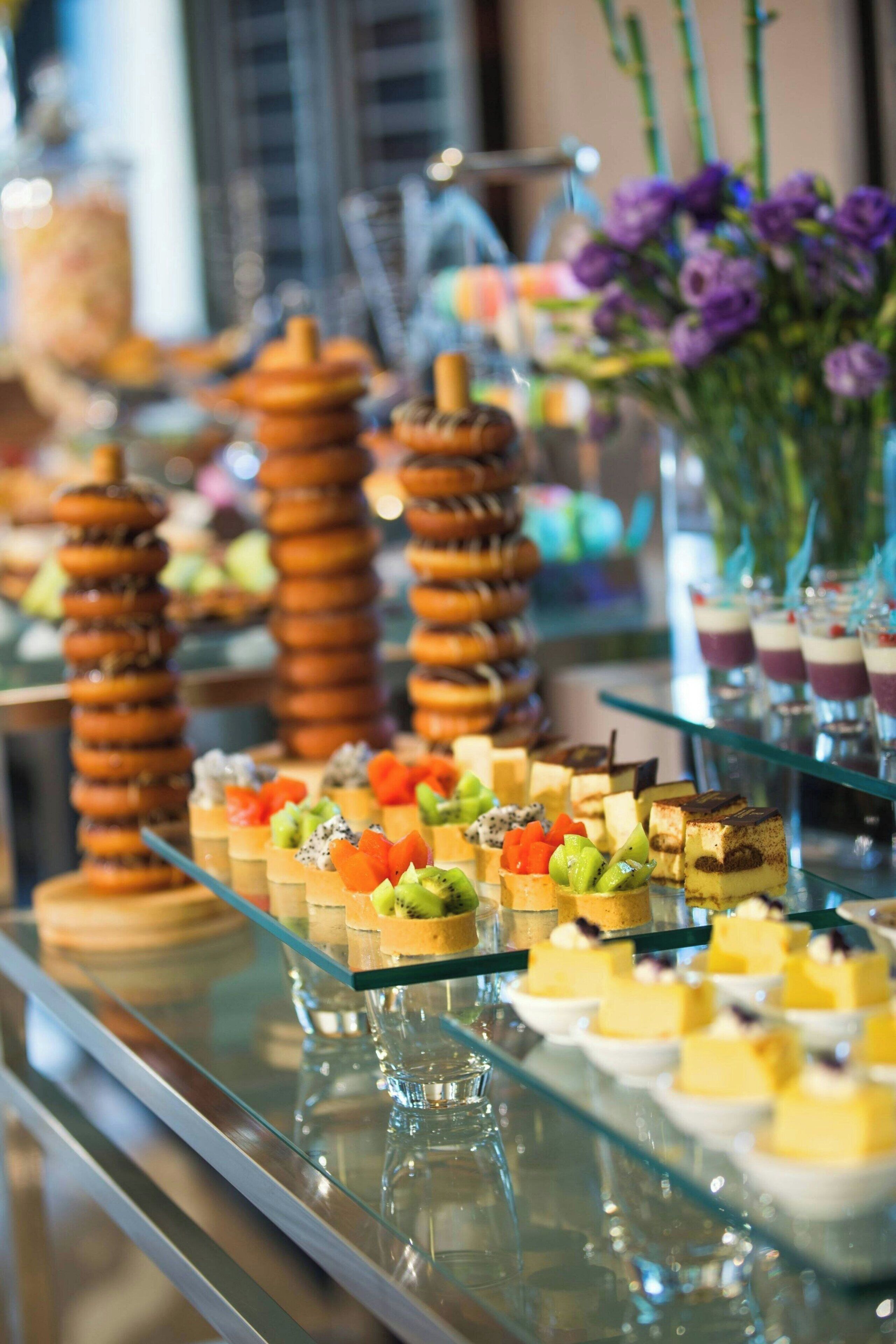 Een buffet met diverse desserts en gebak op glazen schalen.
