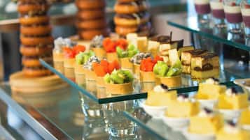 Een buffet met diverse desserts en gebak op glazen schalen.