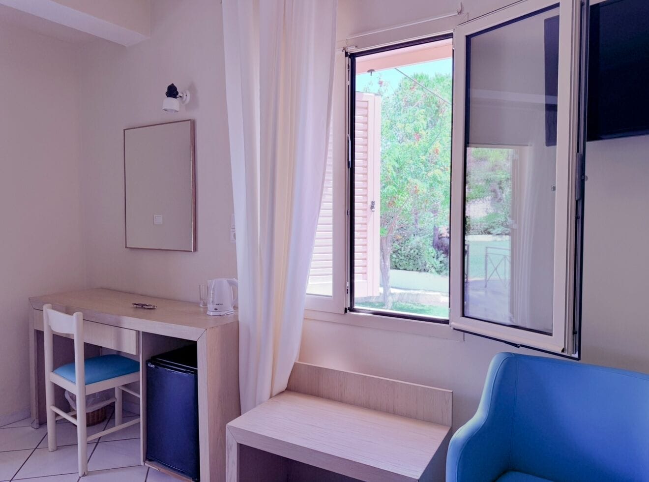 A small room with a desk, chair, and a window with blinds.