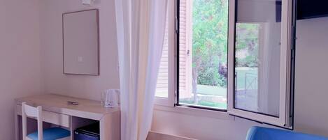 A small room with a desk, chair, and a window with blinds.