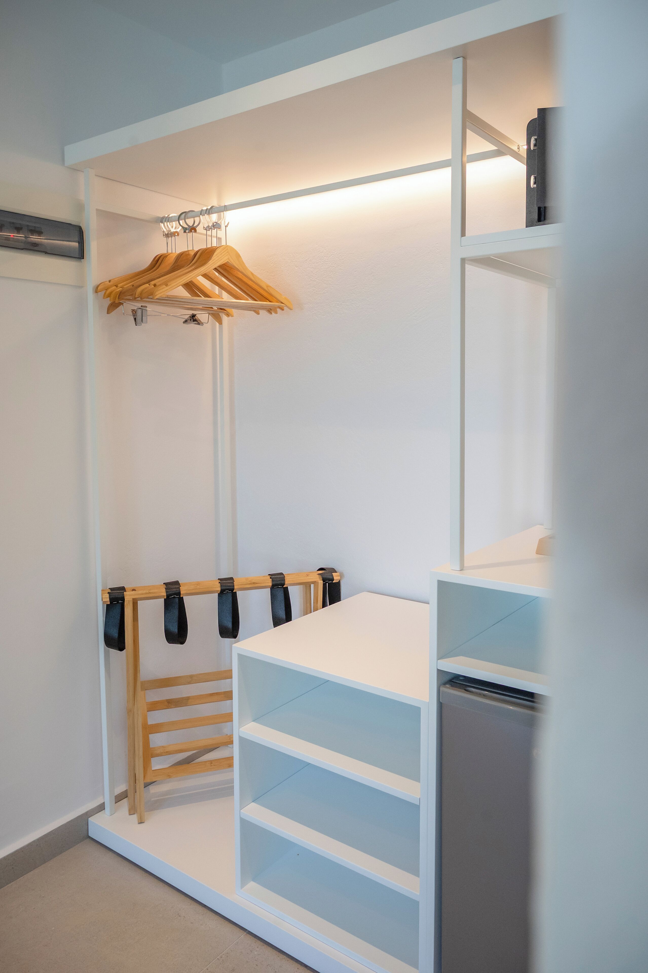A walk-in closet with wooden hangers, shelves, and a built-in appliance.
