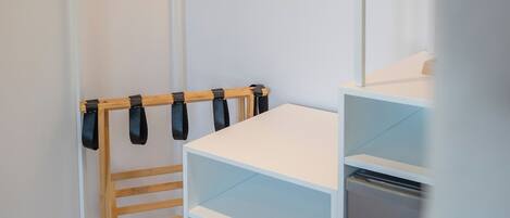 A walk-in closet with wooden hangers, shelves, and a built-in appliance.