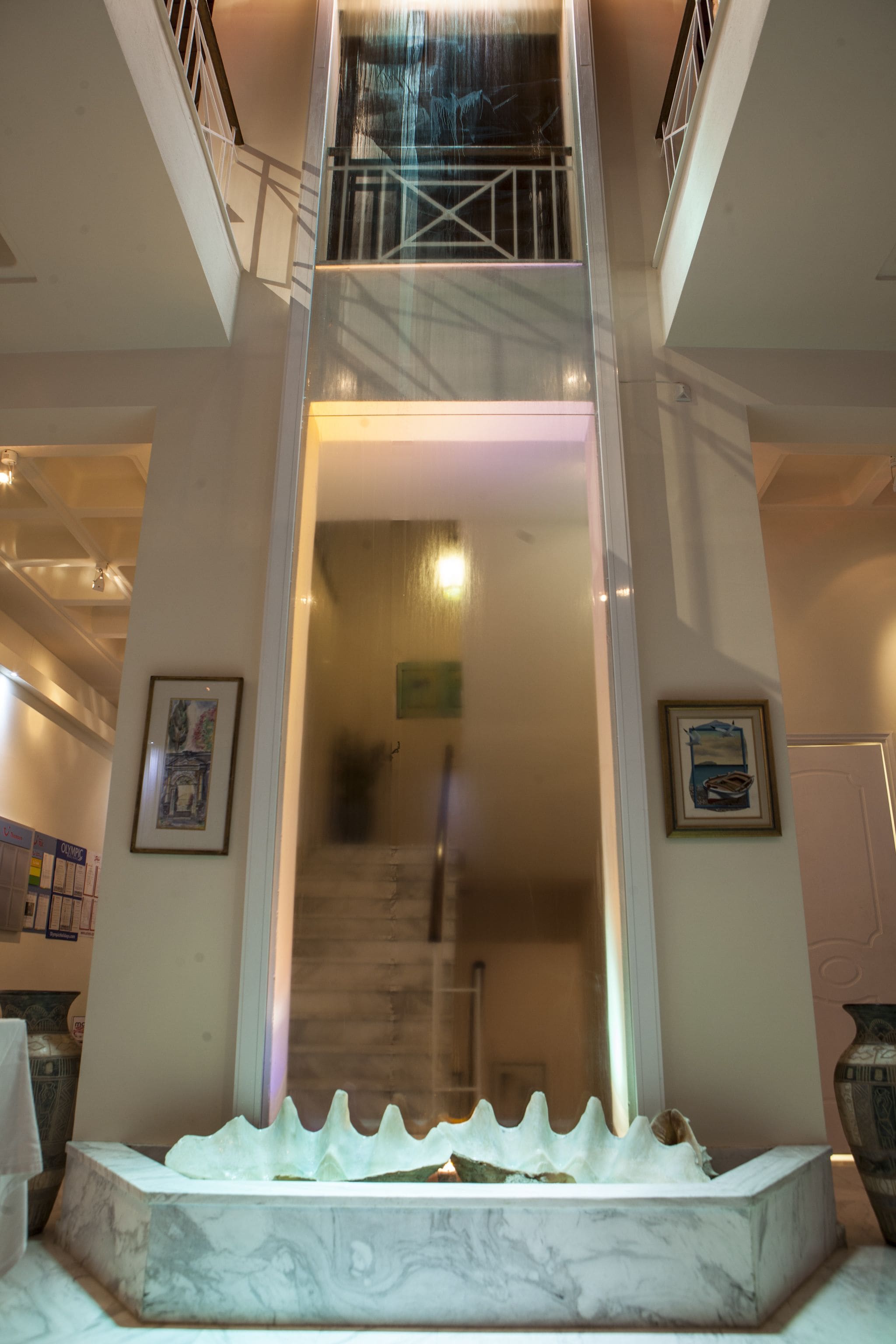 A marble staircase with a glass railing leading to an upper floor.