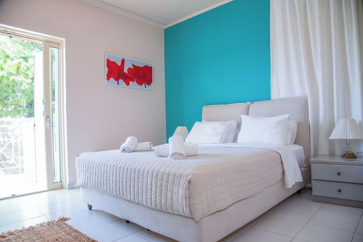 A bedroom with a bed, a nightstand, a lamp, and a door leading to a balcony.