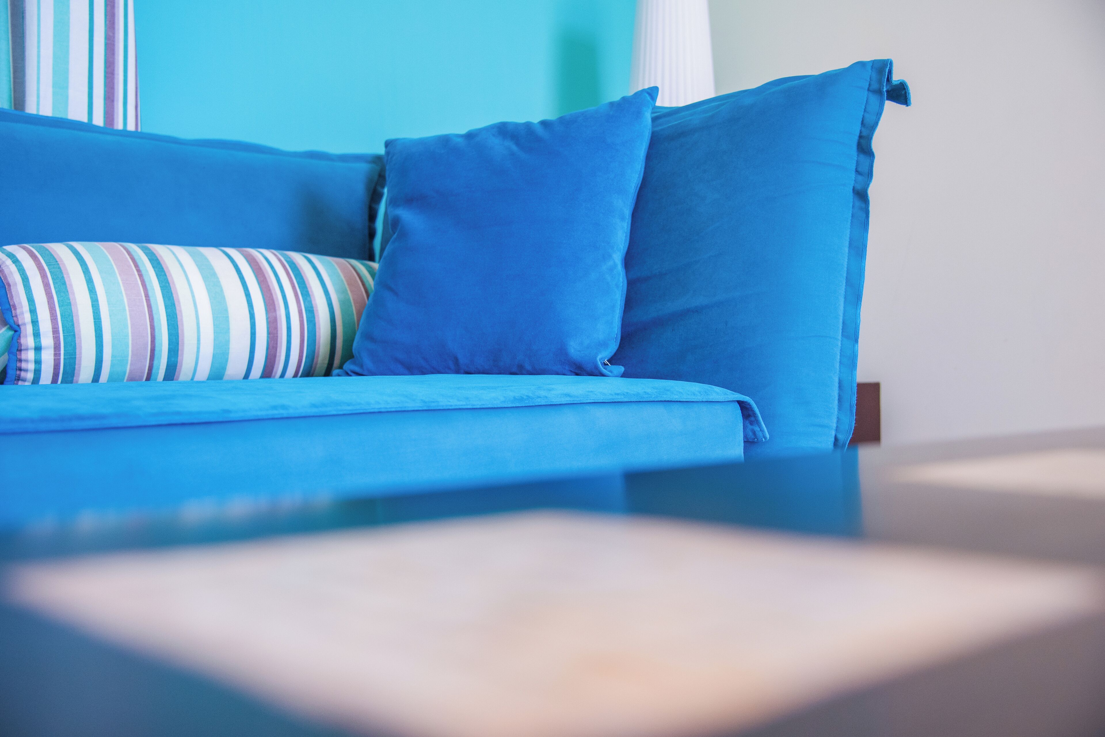 Un canapé bleu avec des coussins à rayures et d’autres de couleur bleu uni.