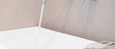 Ein modernes Badezimmer mit einer weißen Badewanne, einem Chrom-Wasserhahn und einer wandmontierten Armatur.