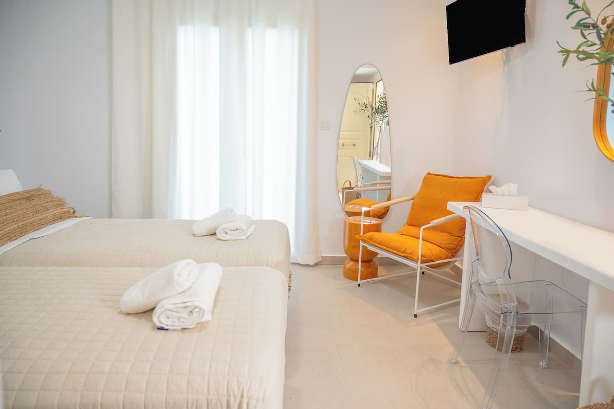 A hotel room with a bed, a desk, a chair, a mirror, and a television.