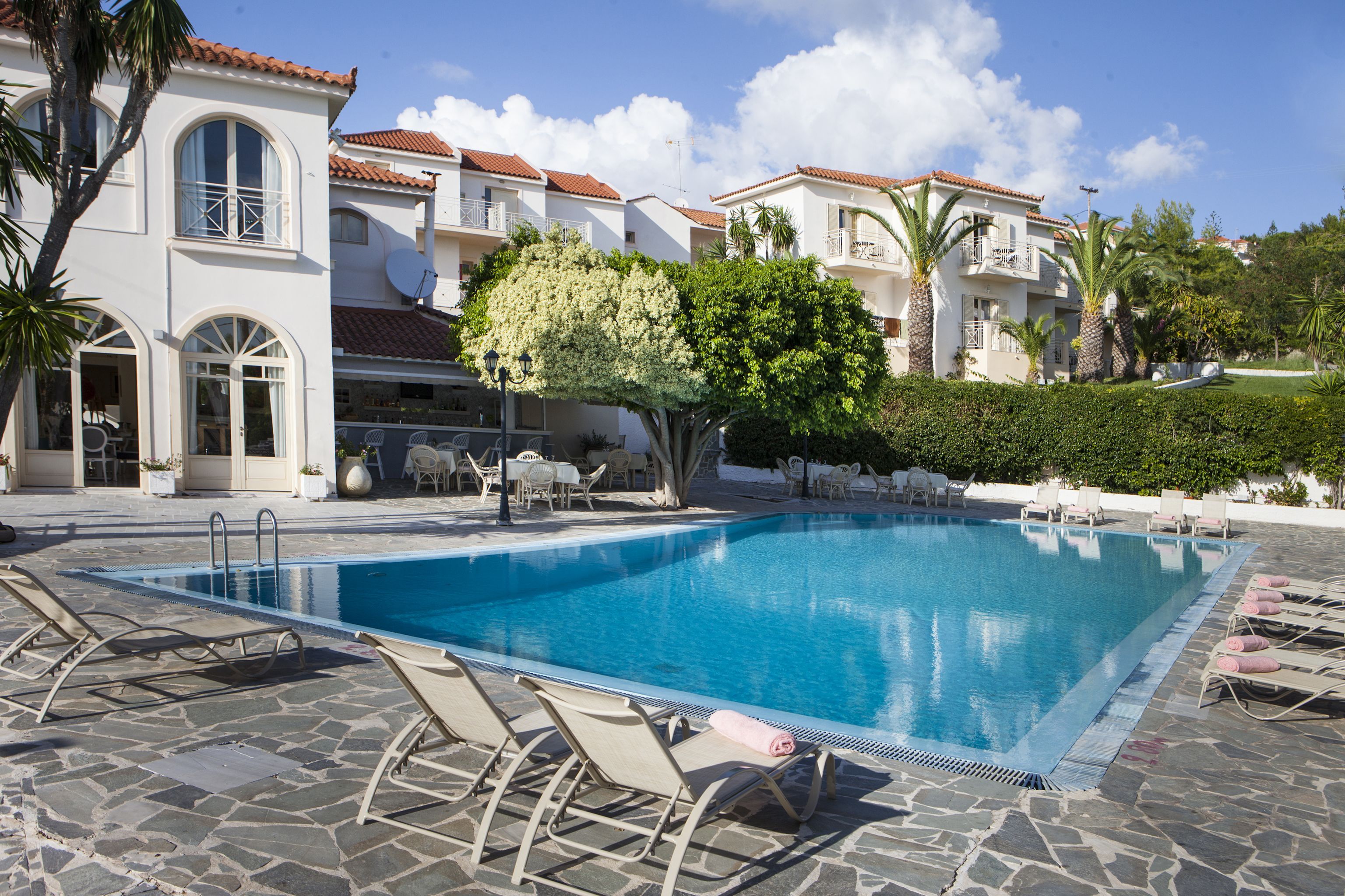 A swimming pool with lounge chairs and a stone patio.