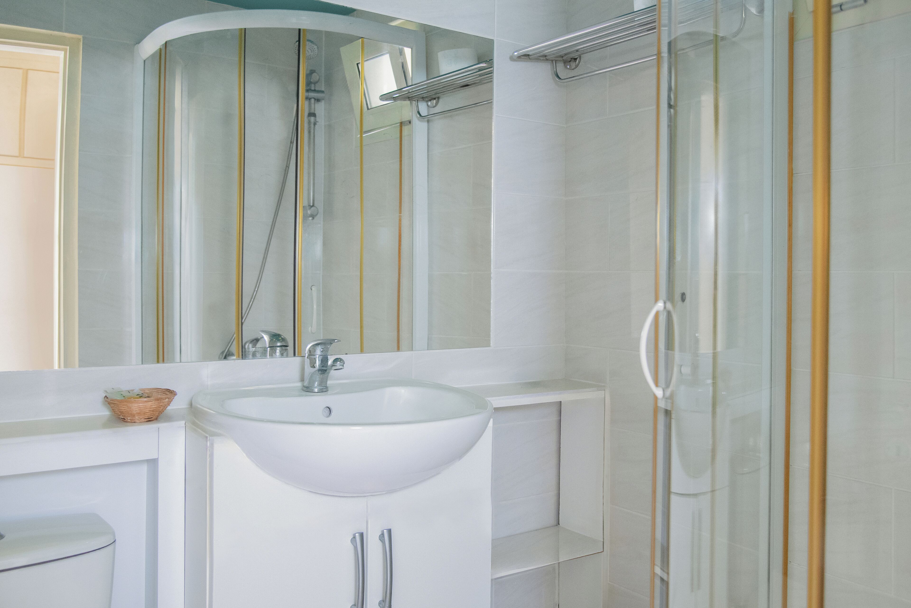 A modern bathroom with a white sink, a glass shower enclosure, and a large mirror.