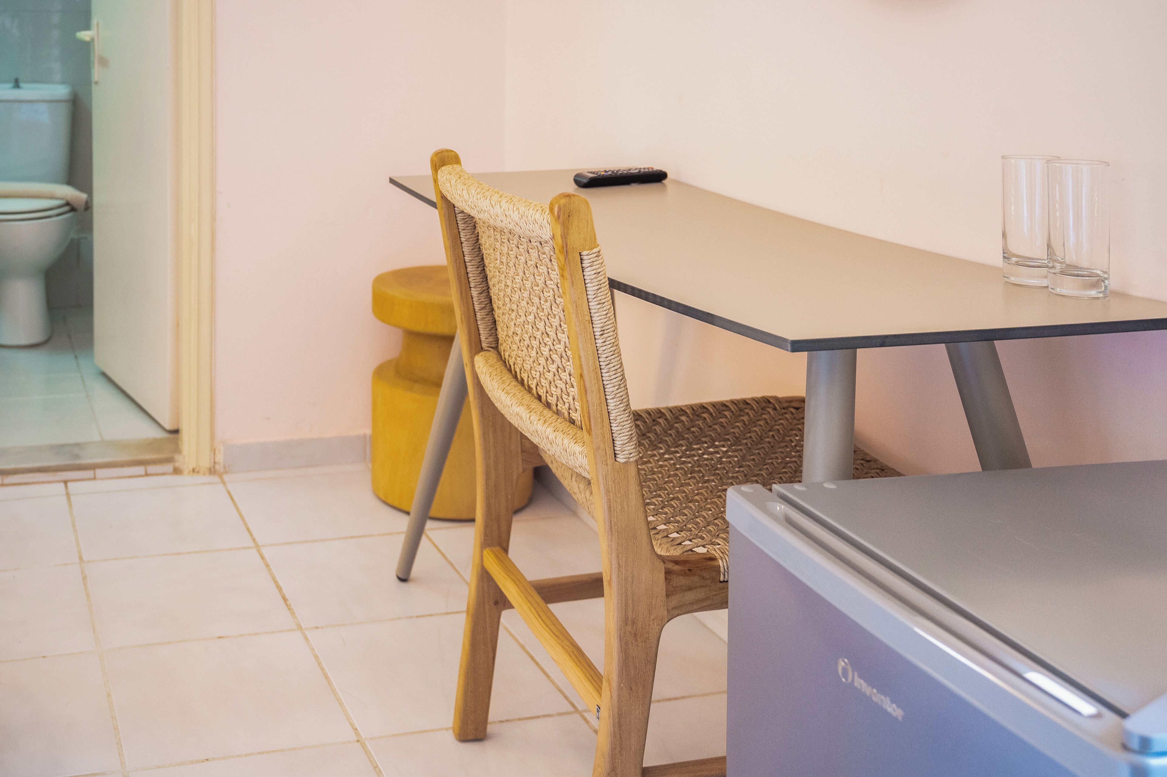 A small room with a table, a chair, a toilet, and a trash bin.