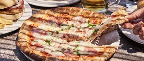 A pizza with cheese, ham, and green peppers on a plate.
