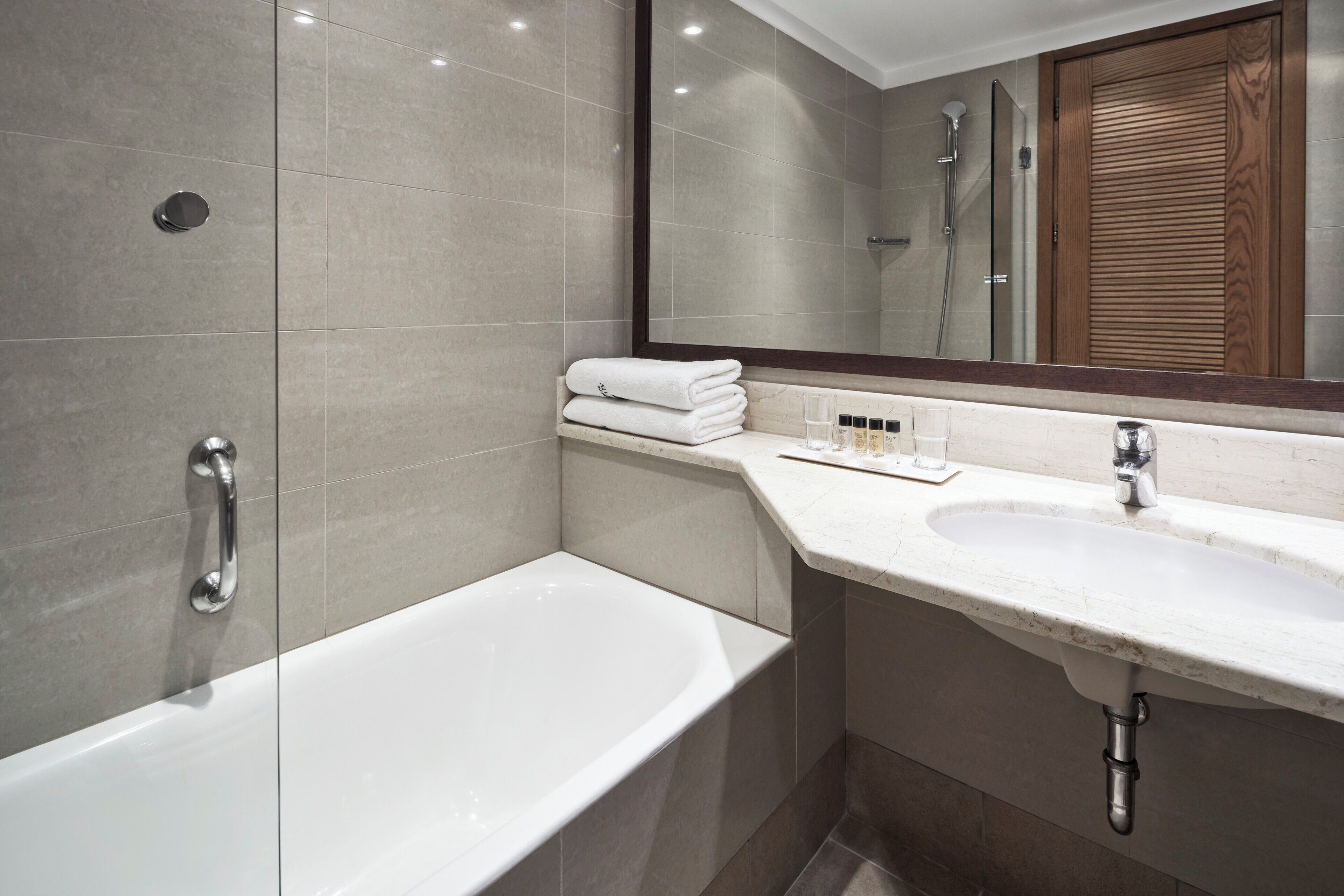 A modern bathroom with a bathtub, a sink, and a mirror.