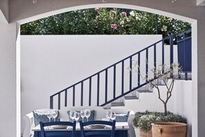 A dining area with a table set for two, a staircase, and a view of a garden with flowers. - Atlantica Beach Resort Kos - All Inclusive (Kos)