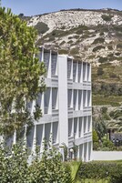 Un edificio moderno con un diseño arquitectónico único, varios balcones y un paisaje montañoso de fondo.