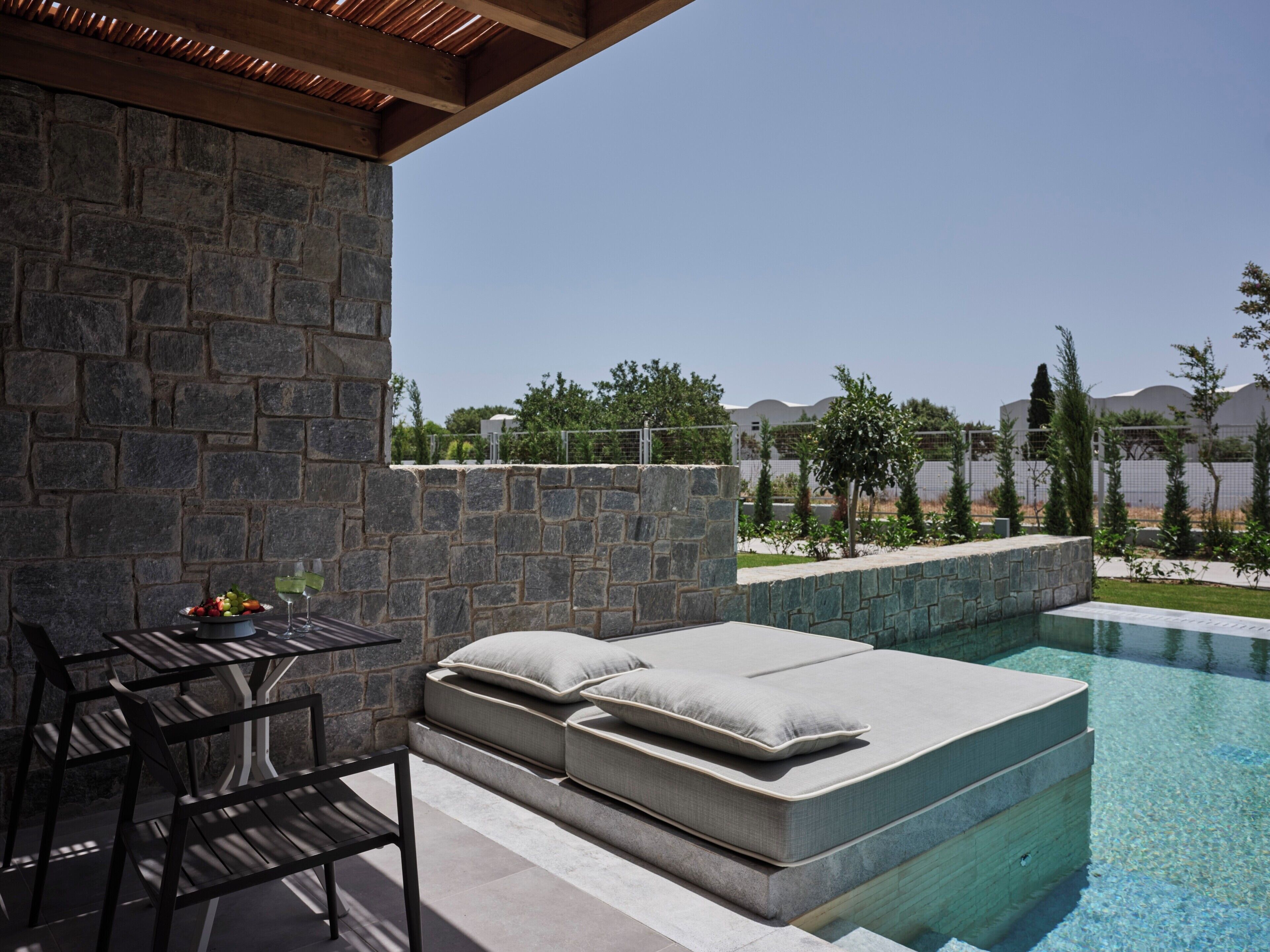 A stone wall, outdoor seating, and a pool.