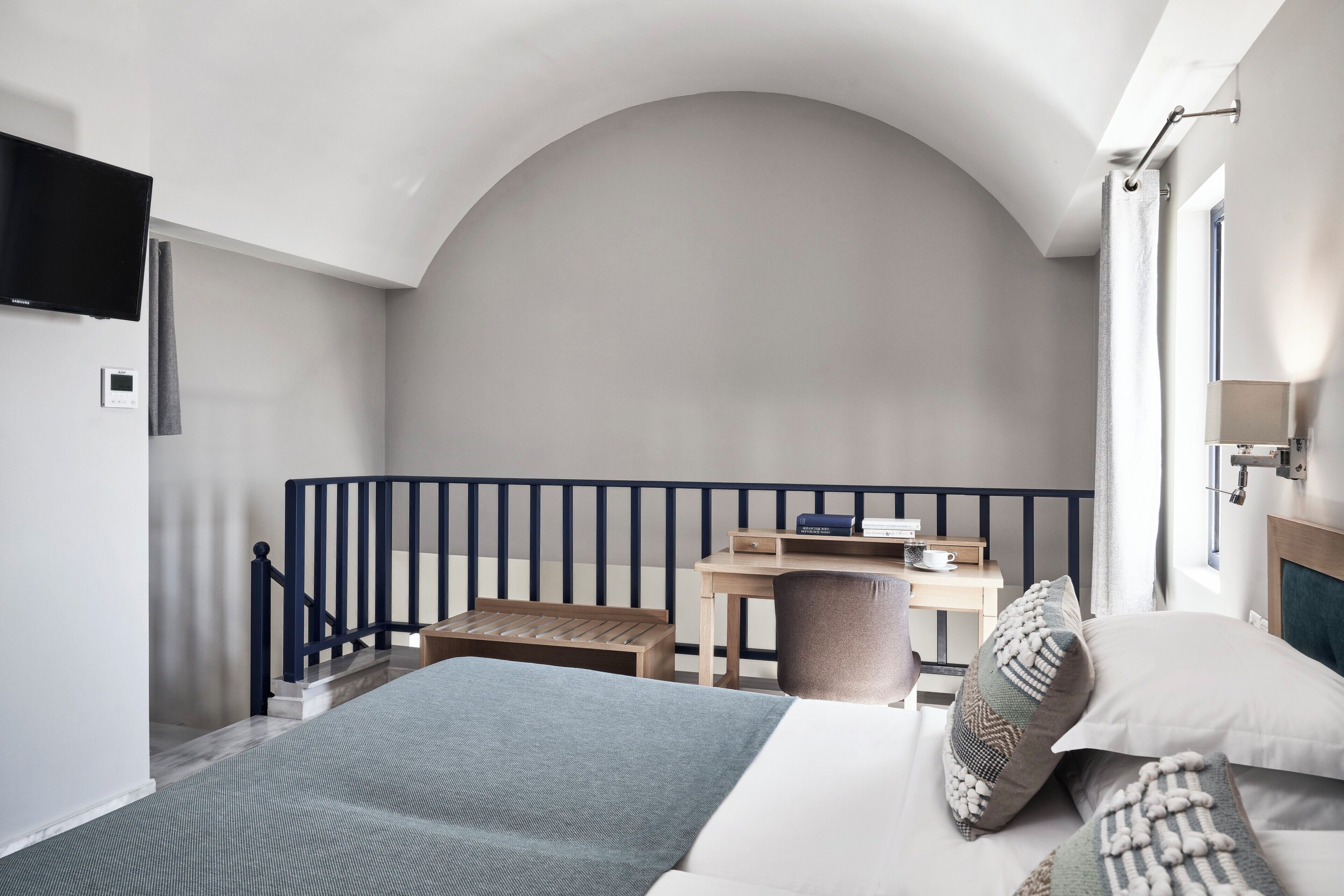Une chambre à coucher comprenant un lit, un bureau, une chaise et donnant sur l’extérieur.