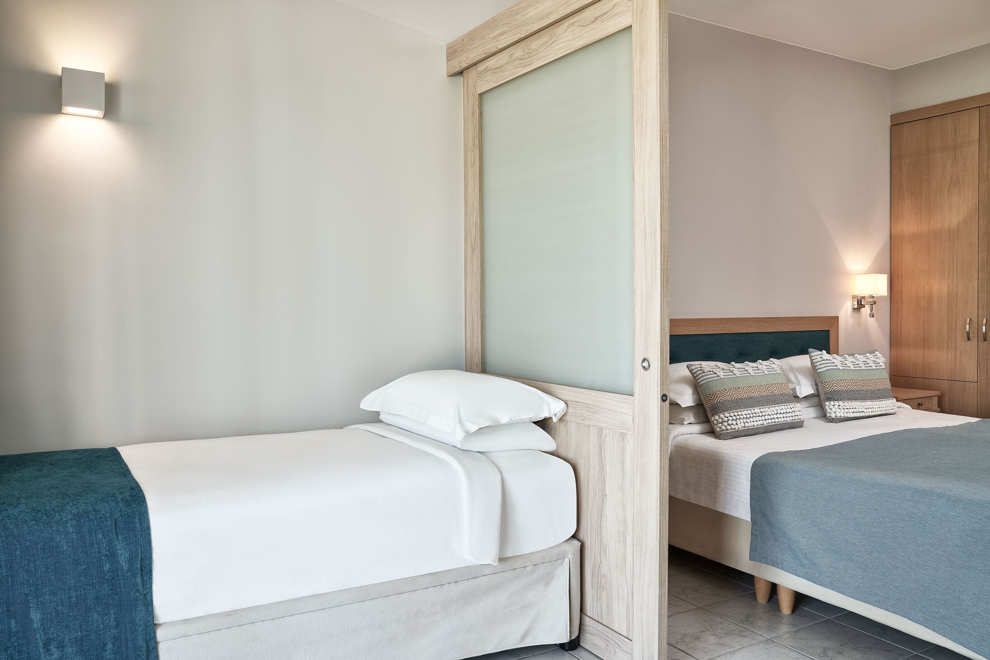A hotel room with two beds, a wardrobe, and a nightstand.
