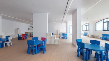 Amplio espacio interior con varias mesas y sillas, piso de madera y grandes ventanales que permiten la entrada de luz natural.
