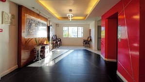 A spacious lobby with a wooden reception desk, a large framed artwork, and a red accent wall. - The Park Residence at Bangkok (Bangkok)