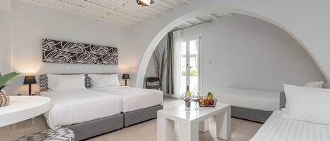 Una habitación de hotel moderna con una cama grande, un sofá, una mesa de comedor y un techo con vigas a la vista.