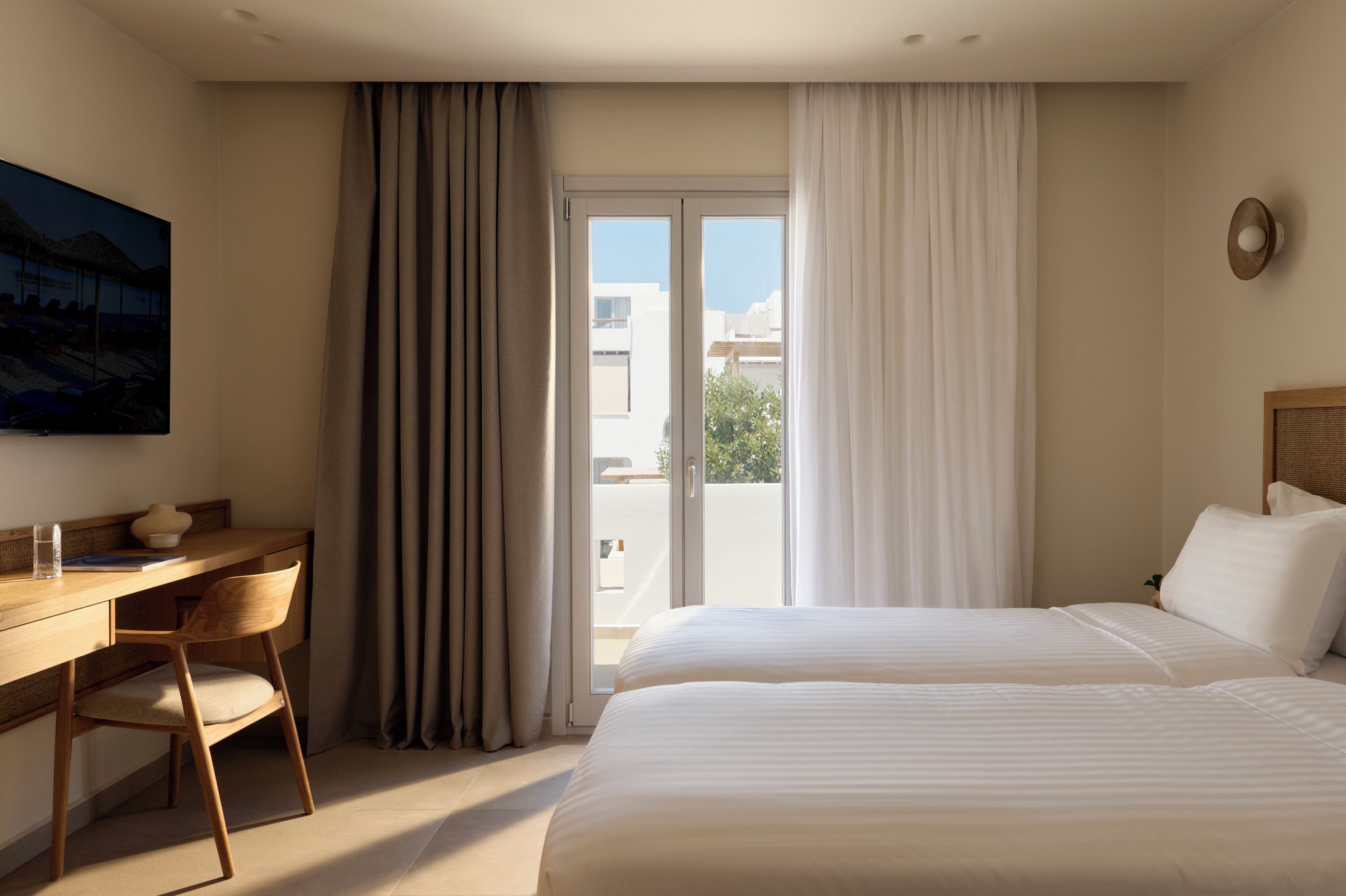 Habitación de hotel con cama, escritorio, silla y vistas al exterior.