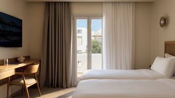 Habitación de hotel con cama, escritorio, silla y vistas al exterior.