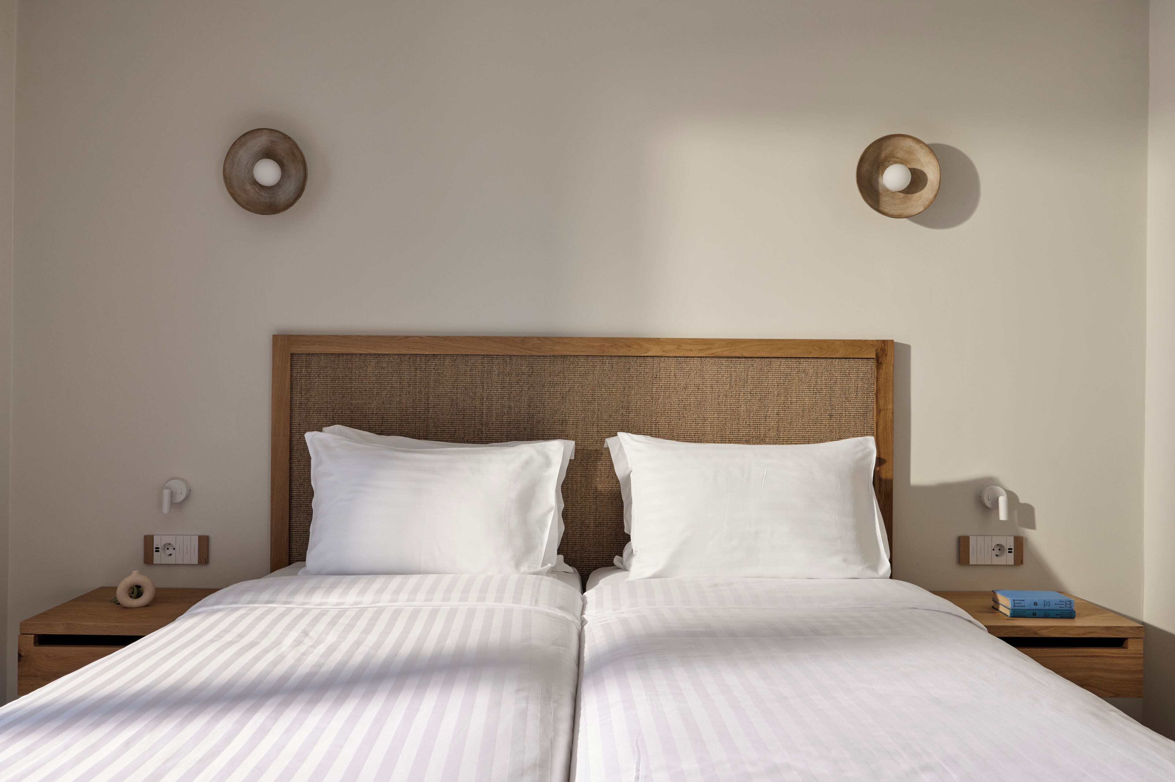 A double bed with a wooden headboard, two white pillows, and a striped bedspread.