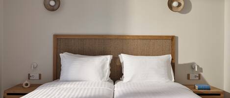 A double bed with a wooden headboard, two white pillows, and a striped bedspread.
