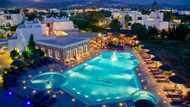 Un resort con una gran piscina, sillas de descanso y vistas del entorno.