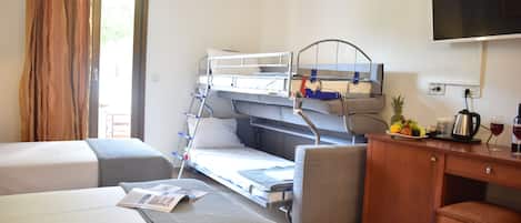 Ein Hotelzimmer mit einem Etagenbett, einem Schreibtisch mit Kaffeemaschine, einem Fernseher und einem Fenster mit Vorhängen.