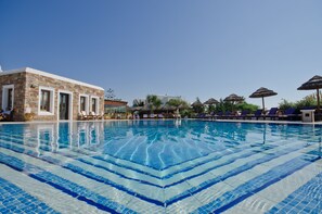 Alberca al aire libre, sombrillas en la alberca y camastros 