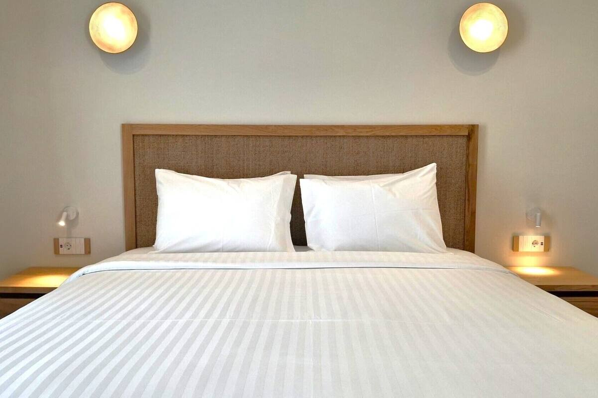 A hotel room with a large bed, two bedside lamps, and a headboard.