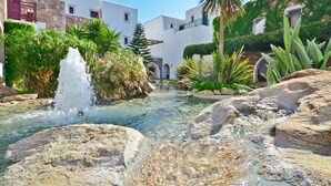 Un patio con fuente de agua cristalina, rodeado de edificios blancos con balcones y follaje.