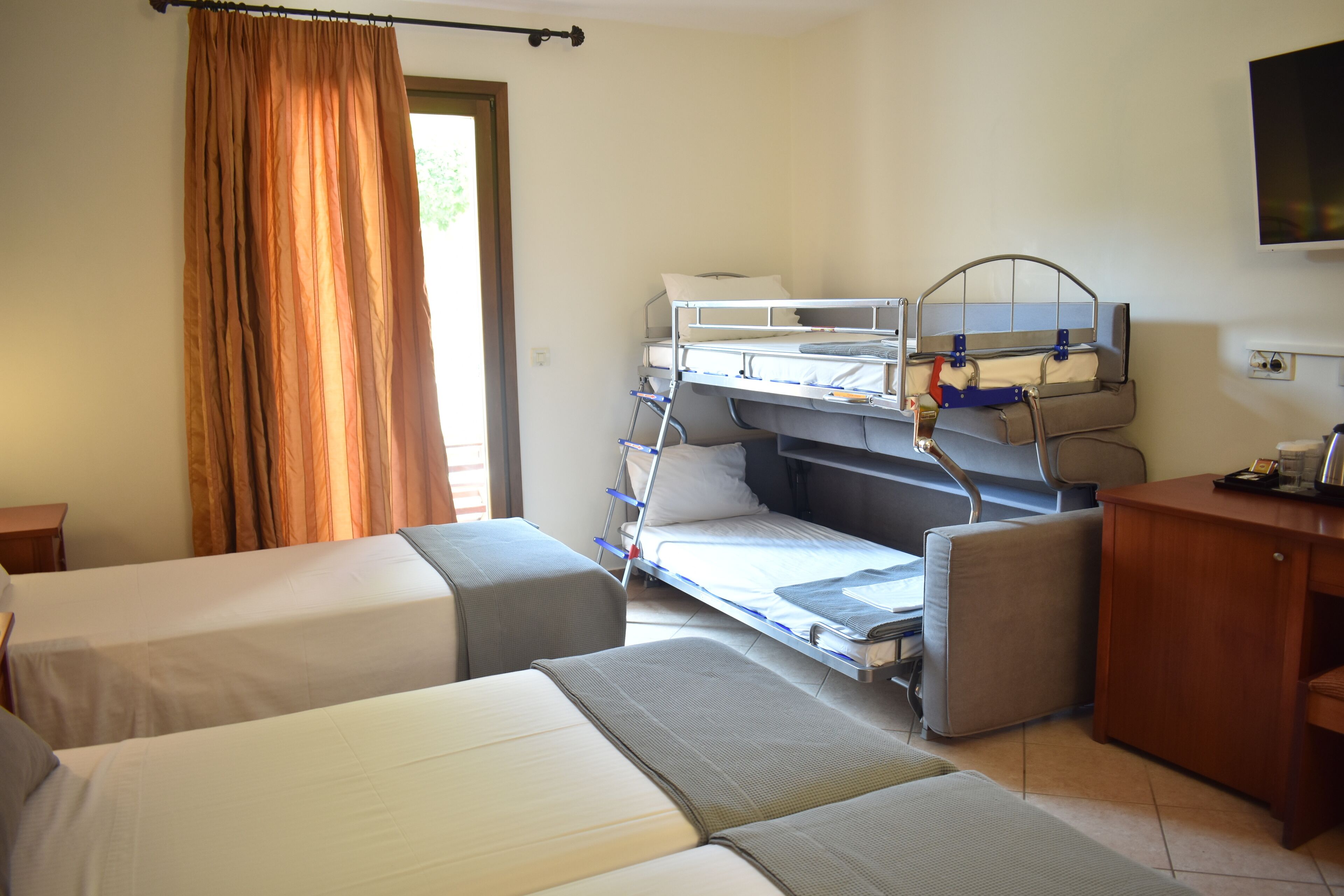 Een hotelkamer met stapelbedden, een bureau en een televisietoestel.