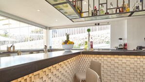 Eine moderne Bar mit einer Steinwand, einer großen Obstschale und Barhocker.