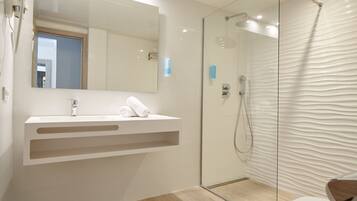 A modern bathroom with a glass shower enclosure, a white vanity with a mirror, and a wooden floor.