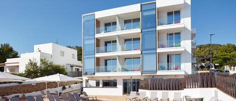 A modern building with a pool area, including lounge chairs and a clear blue pool.
