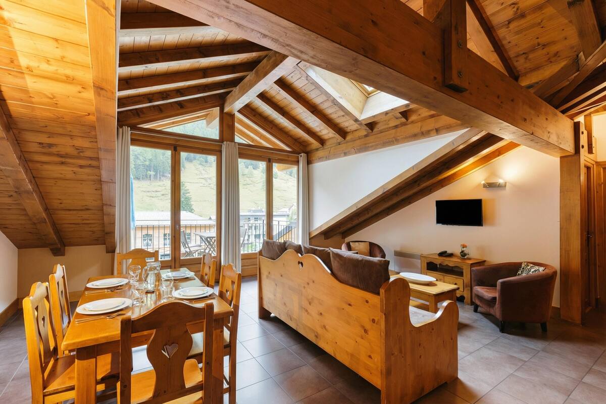 Un intérieur en bois comprenant un coin repas, un canapé et un téléviseur.