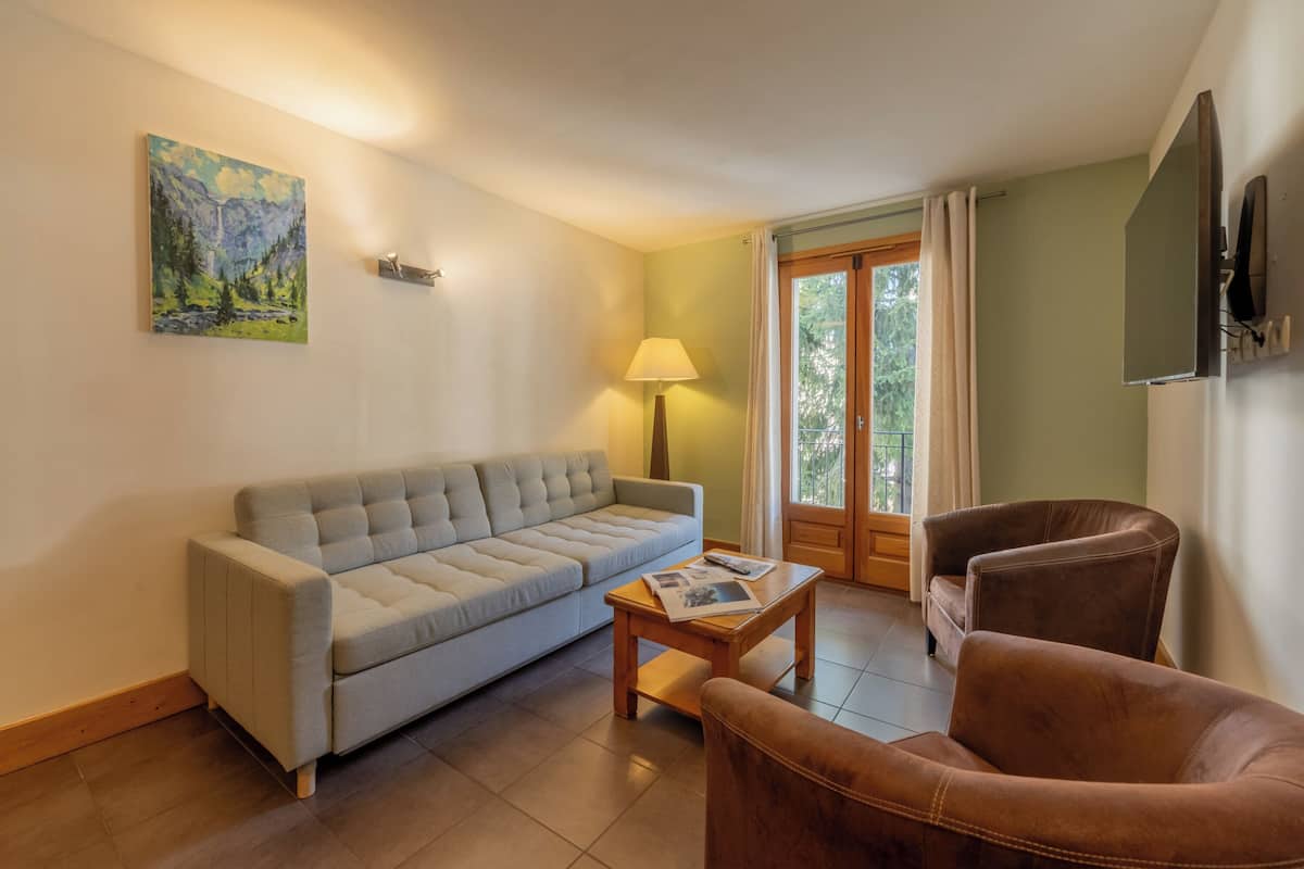 Un salon avec un canapé, une table basse, une lampe et un téléviseur.